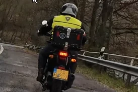 Motorrijder met een reflecterende jas op een bochtige hobbel weg.